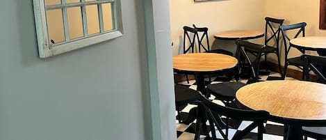 Un interior de restaurante con suelo a cuadros, mesas redondas y sillas negras.