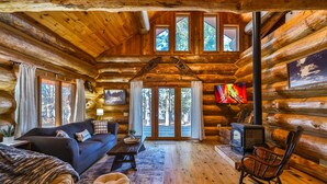 A log cabin interior with a sofa, rocking chair, and a fireplace. - Retreat at Blueberry (Osage)