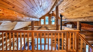A wooden cabin with a loft bedroom, a wooden staircase, and a large window. - Retreat at Blueberry (Osage)