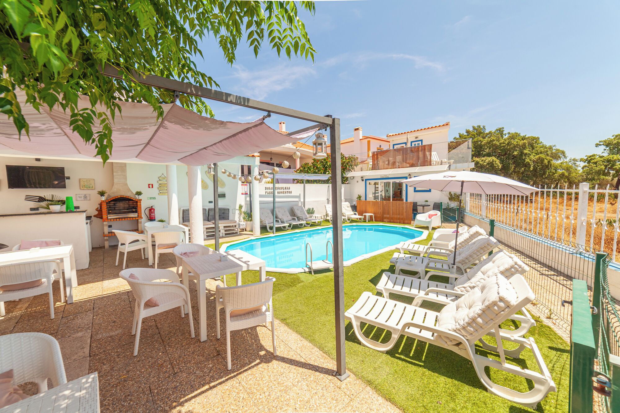 Un espace aménagé au bord de la piscine, avec des chaises longues, un barbecue et une piscine.