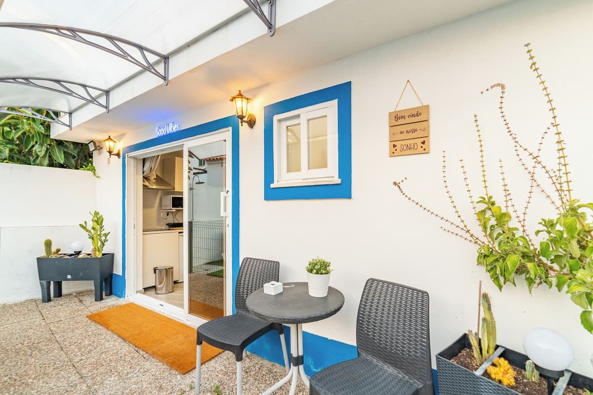 A patio area with a table and chairs, a small potted plant, and a sign on the wall.