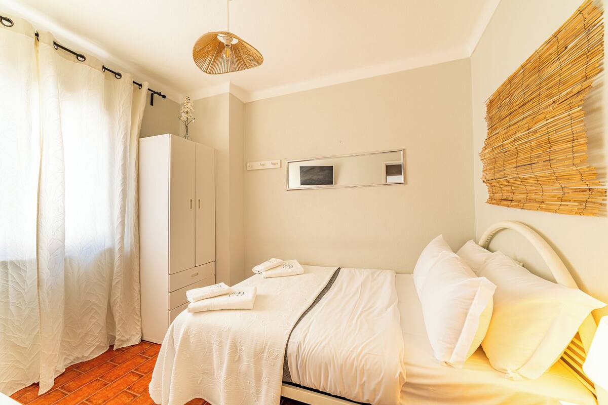 A neatly arranged bedroom with a bed, a wardrobe, and a mirror on the wall.