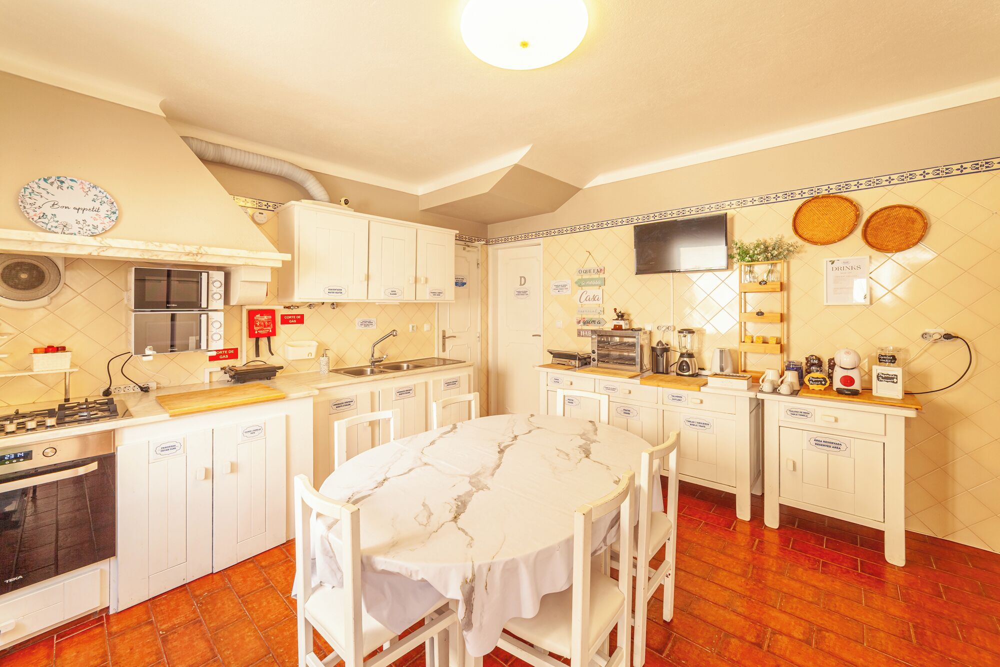 Una cocina compacta con gabinetes blancos, estufa a gas, microondas y cafetera.