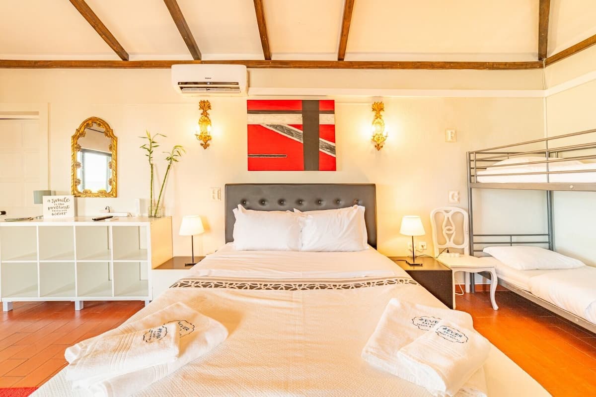 A hotel room with a large bed, a smaller bed, a desk, and a bunk bed.