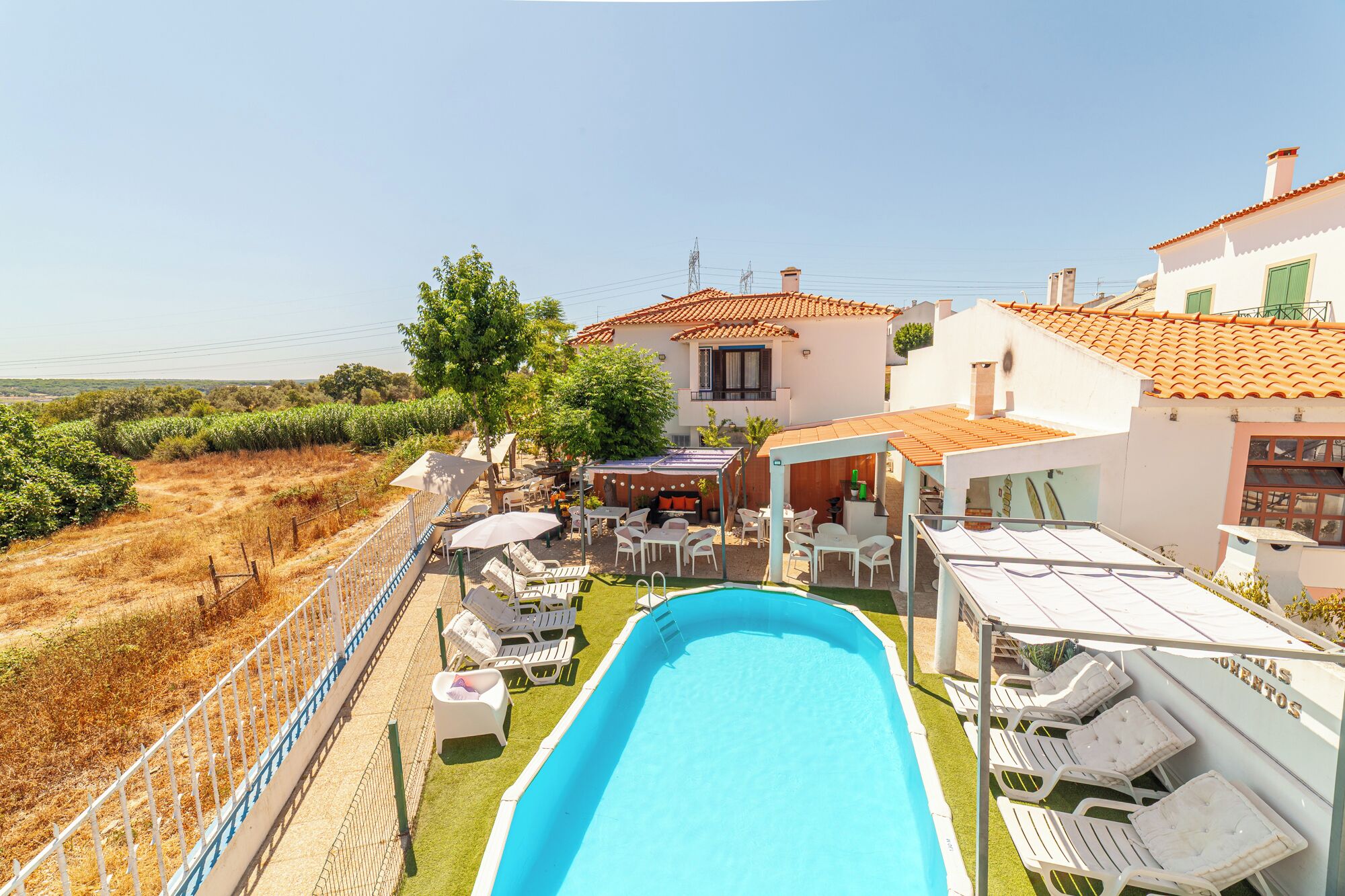 Zona junto a la piscina con sillones de descanso, una piscina y vistas al campo.