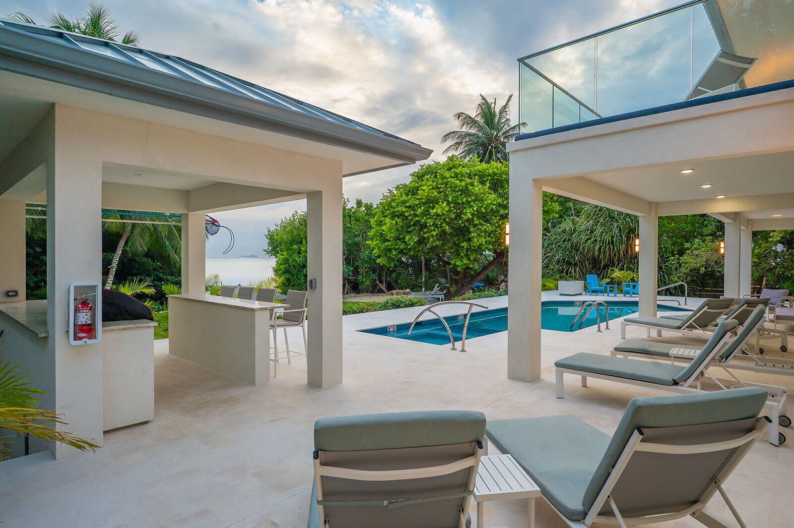 A poolside area with lounge chairs, a bar, and a view of the ocean.