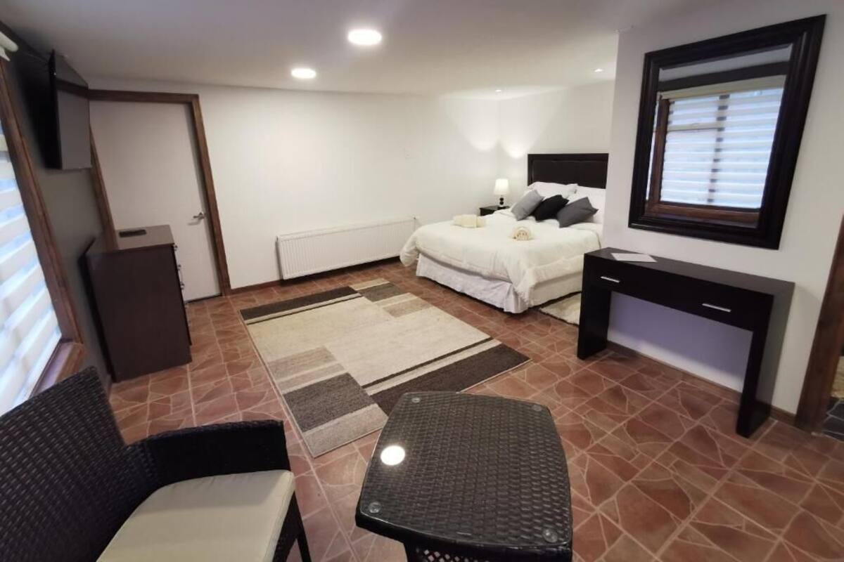 A bedroom with a bed, bedside table, chair, and a small table.