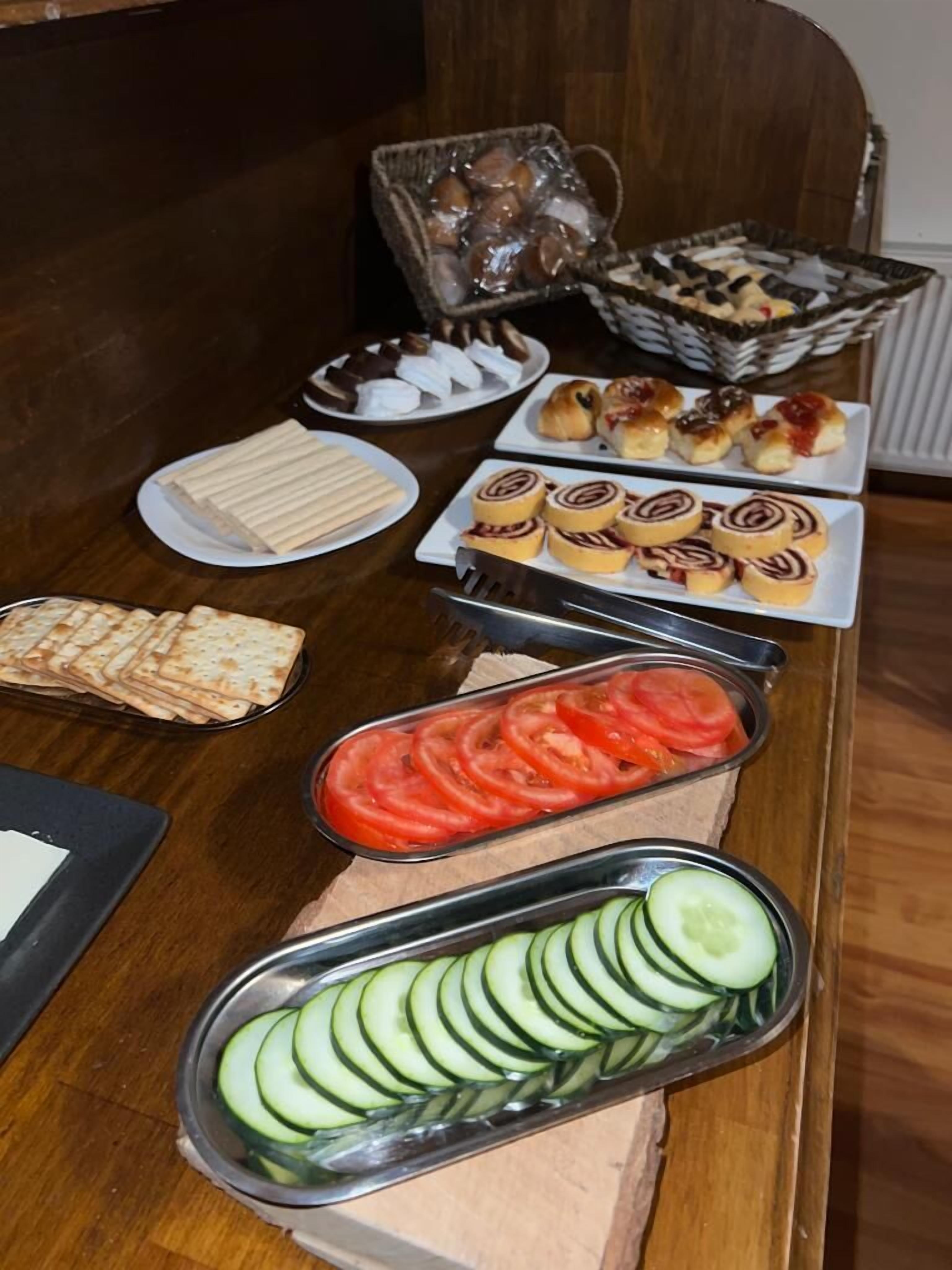 Ein Buffet mit verschiedenen Speisen, darunter Gebäck, Sandwiches und geschnittenem Gemüse.
