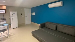 A compact living space with a kitchenette, a grey sofa, and a blue accent wall. - Kariris Blue Tower (Crato)