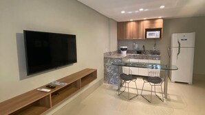 A modern kitchen with a TV, a dining area, and a refrigerator. - Kariris Blue Tower (Crato)