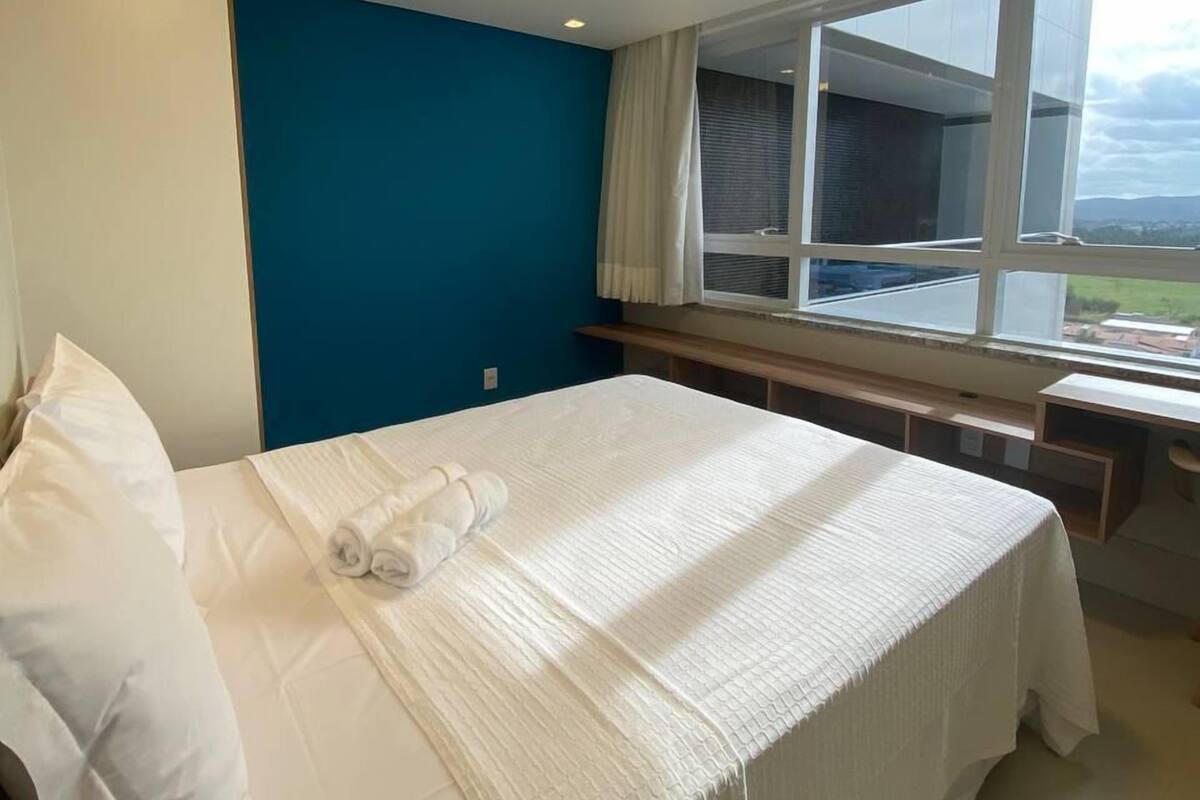 Habitación de hotel con cama, escritorio y ventana que ofrece vista a un edificio y paisaje.