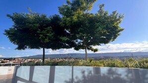 A modern building with a curved wall and a large tree in the foreground. - Kariris Blue Tower (Crato)