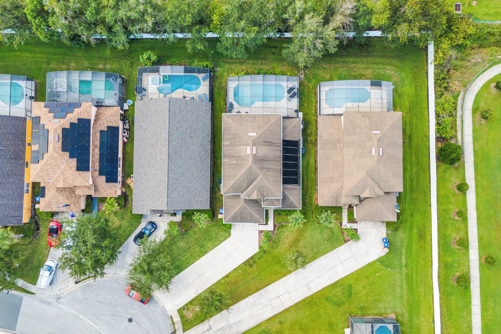 Luchtbeeld van een woonwijk met huizen, een zwembad en een oprit.