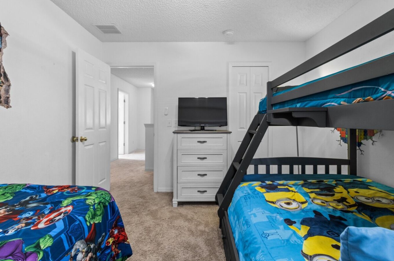 A child's bedroom with bunk beds, a dresser, and a television.