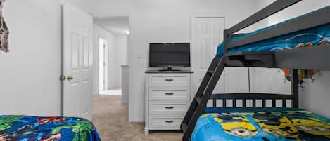 A child's bedroom with bunk beds, a dresser, and a television.