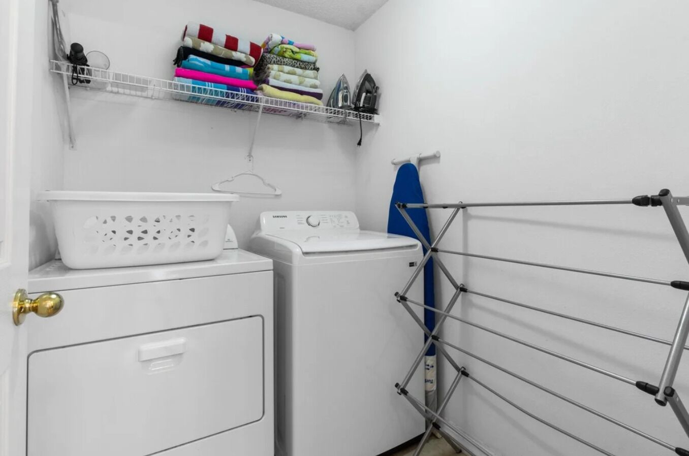 A laundry room with a washing machine, dryer, and a drying rack.