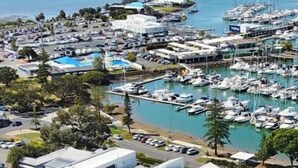 A marina with numerous boats docked, surrounded by modern residential buildings with solar panels. - Great size close to the action (Manly)