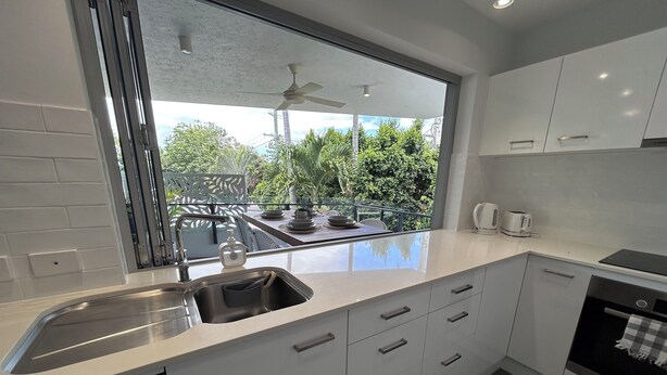 A modern kitchen with a large window, white cabinetry, and a built-in dishwasher. - Great size close to the action (Manly)