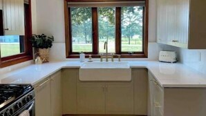 Una cocina con ventana, un lavamanos, armarios y una estufa.