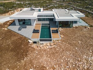 A modern house with a swimming pool, large windows, and a flat roof.
