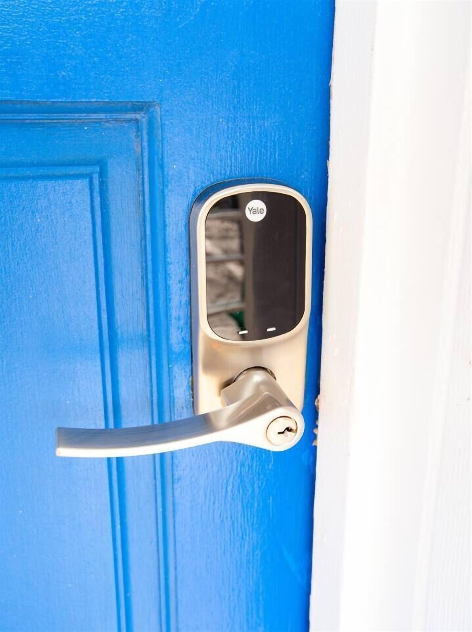Una puerta azul con una cerradura inteligente Yale y una mirilla.