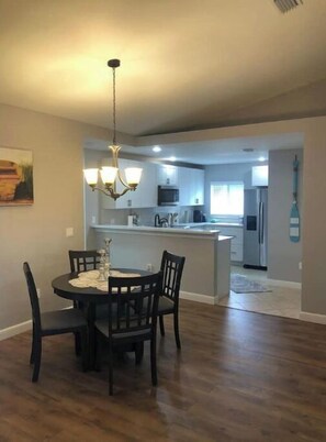 Enjoy meals in this dining area with a round table and four chairs, surrounded by a kitchen and a chandelier.
