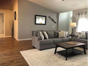 Relax in this inviting living room with a grey sofa, coffee table, and rug, perfect for unwinding.