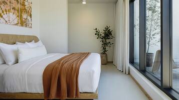 A modern bedroom with a large bed, a potted plant, and a view of the outdoors through large windows.