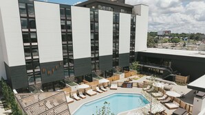 Un hotel moderno con piscina en la azotea, zona de estar al aire libre y vistas de la ciudad.