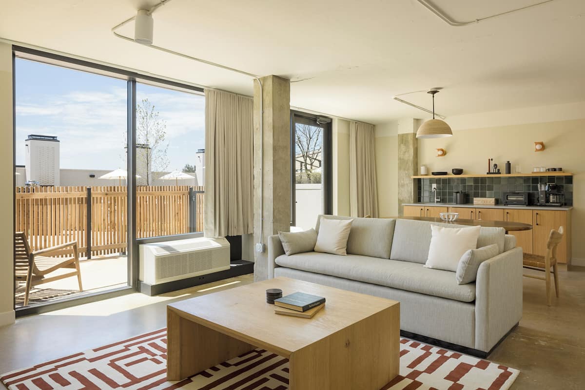 A modern living room with a sofa, coffee table, and a view through large sliding glass doors to an outdoor patio.