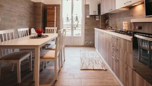 Eine moderne Küche mit Holzschränken, einem Gasherd und einem Essbereich mit weißem Tisch und Stühlen.