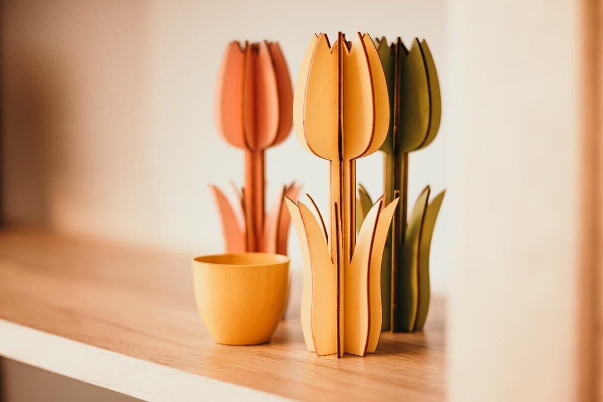 A wooden shelf with a yellow bowl and a set of paper flowers.