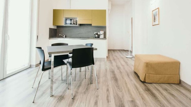 Una cocina moderna con comedor, una cafetera y un taburete pequeño.