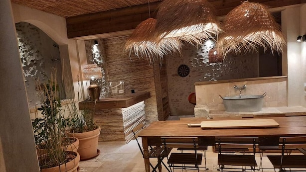 A rustic kitchen with a wooden table, chairs, and potted plants.