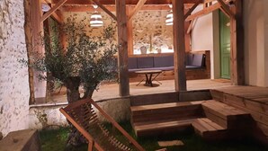 A wooden pergola with a bench, a table, and a sofa under a tiled roof.