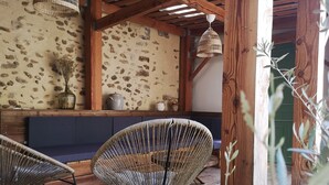 A rustic interior with a stone wall, wooden beams, a woven chair, and a hanging light fixture.