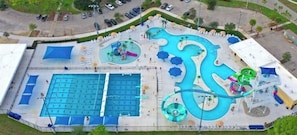 Relax by the large rectangular pool with multiple lanes, surrounded by lounge chairs and umbrellas.