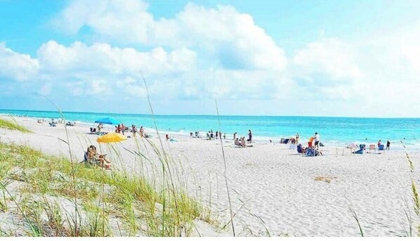 Guests can enjoy a serene beach experience with access to the ocean and shaded areas under umbrellas.