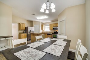Enjoy cooking and dining in this well-equipped kitchen with a range hood, refrigerator, and oven, adjacent to a dining area with a table and chairs.