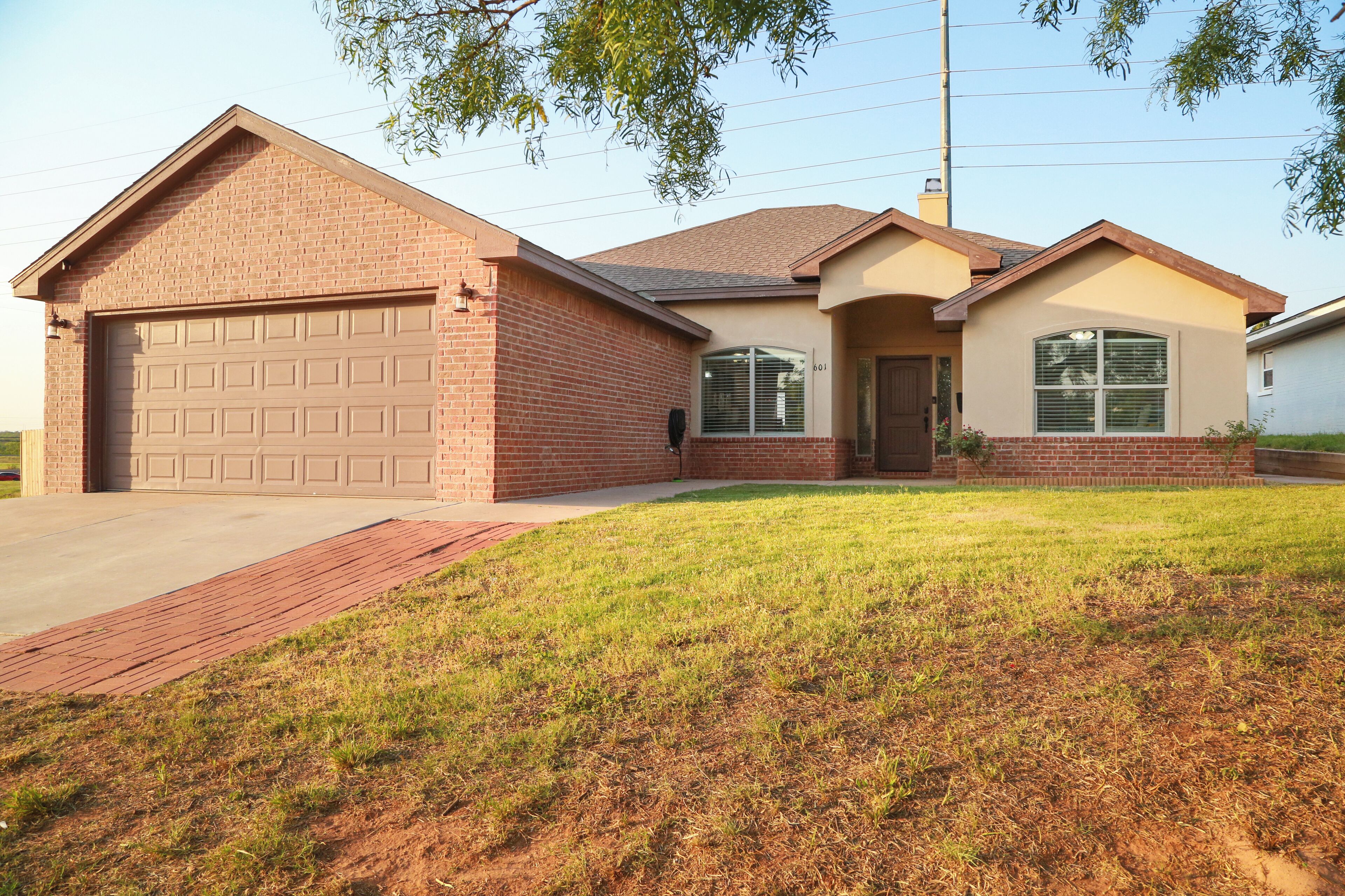 A two-story house with a garage, a front porch, and a well-maintained lawn.