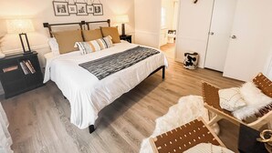 A bedroom with a bed, nightstands, a ceiling fan, a door, and a wall-mounted picture frame. - The Lookout at Lakewood, Lakefront Paradise with Ultimate Entertainment, Hot Tub and Dock (Bridgeport)
