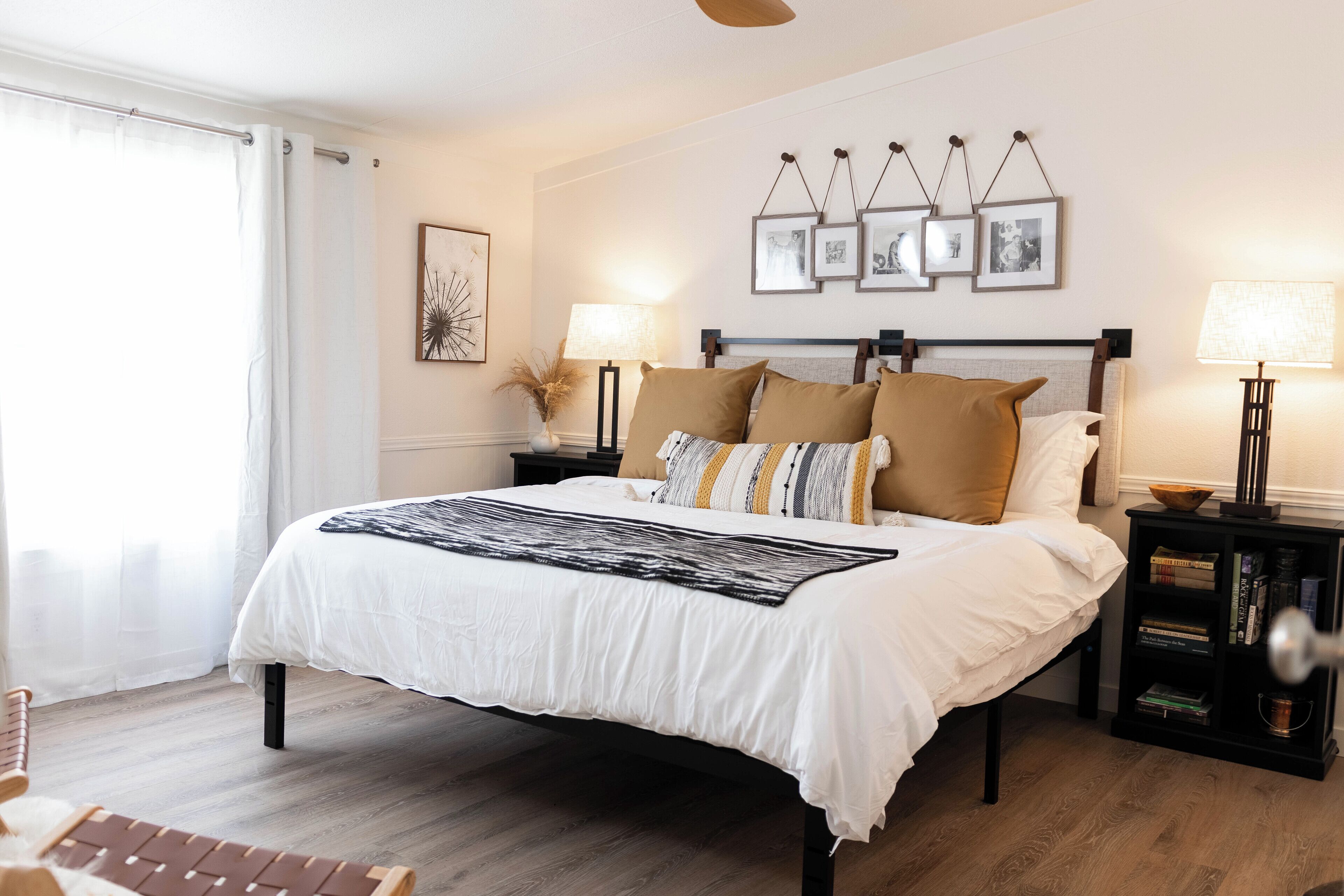 A bedroom with a large bed, bedside tables, a lamp, and a bookshelf.