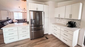 A modern kitchen with white cabinetry, a stainless steel refrigerator, and a coffee maker on the countertop. - The Lookout at Lakewood, Lakefront Paradise with Ultimate Entertainment, Hot Tub and Dock (Bridgeport)