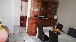 A dining area with a wooden cabinet, a table, and chairs. - Sandra Home (El Puerto de Santa María)