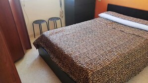 A bedroom with a bed, a wardrobe, and two stools. - Sandra Home (El Puerto de Santa María)