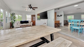 Un salón amplio con una mesa de comedor de madera, un sofá y un ventilador de techo.