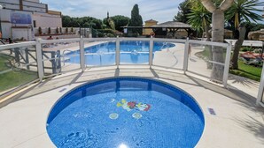 A round swimming pool with a tiled edge, surrounded by a white fence and a clear view of the surrounding area.