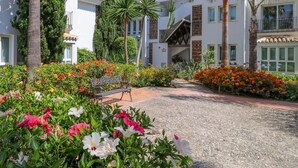 A courtyard with a gravel path, benches, and a variety of flowers. - Beachfront with large garden  - Los Monteros Palm Beach (Marbella)