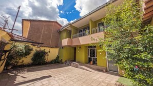 A two-story building with a balcony and a paved courtyard. - Pikaflor Cerezo mini apartment (Cusco)