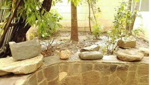 A stone-walled area with a large bowl on a ledge, surrounded by rocks and sparse vegetation. - Pikaflor Cerezo mini apartment (Cusco)